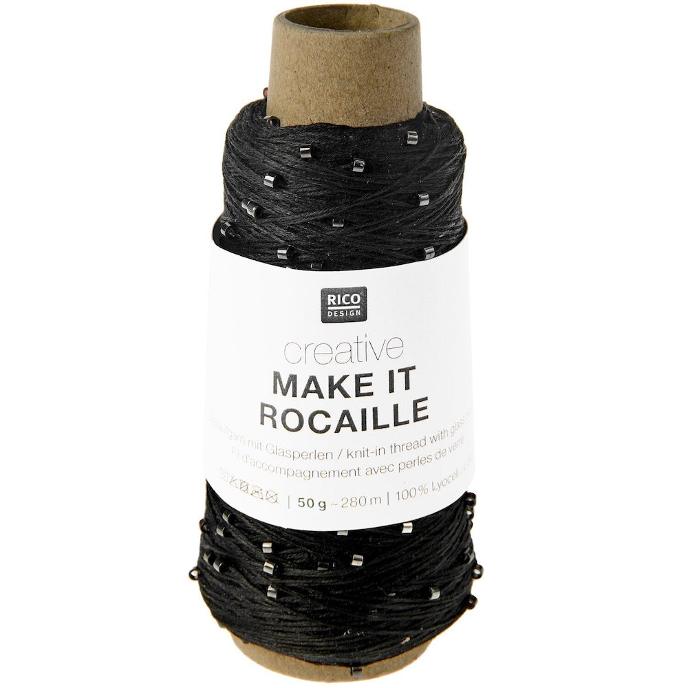 A spool of black knitted thread with small silver rhinestones, wrapped around a brown cardboard core with a white paper label that reads 'RICO DESIGN creative MAKE IT ROCAILLE'.