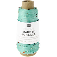 A spool of mint green knitted thread with small colorful beads, wrapped in a white paper label that reads 'RICO ROLLS creative MAKE IT ROCAILLE'.