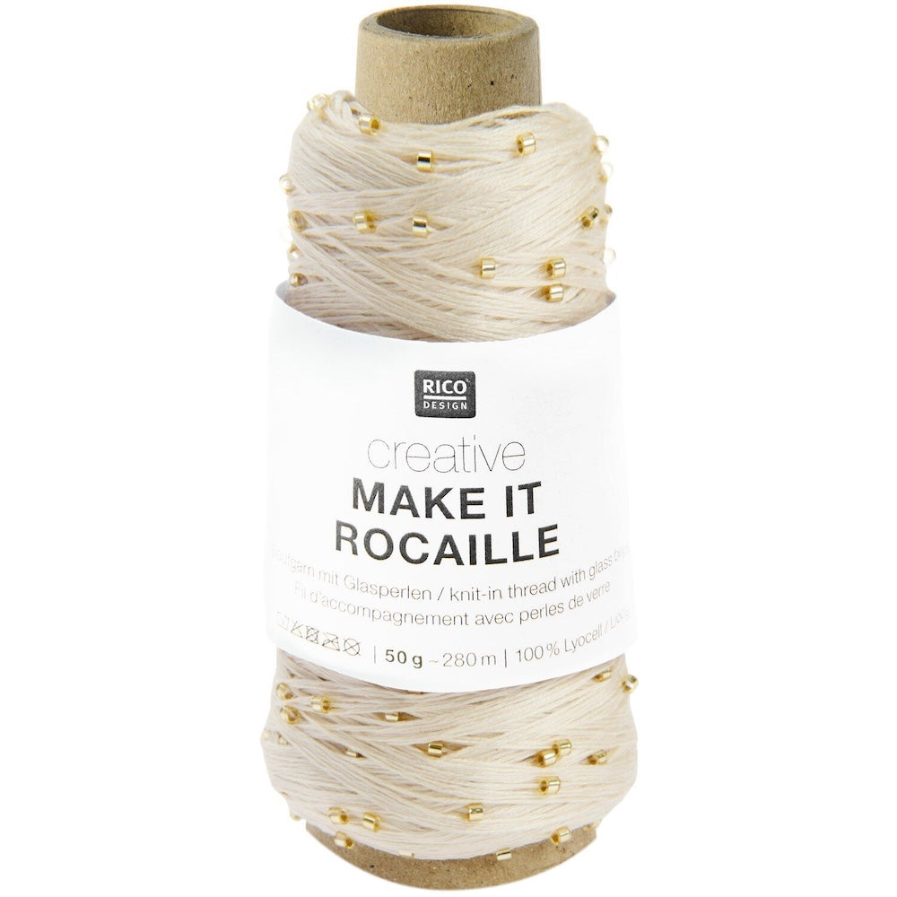 A spool of Rico Design Creative Make It Rocaille yarn thread, featuring a cream-colored thread with small gold beads and a white paper label.